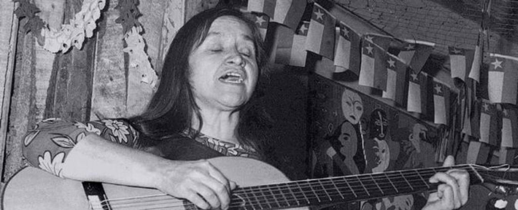 Violeta Parra tocando guitarra frente a la camara