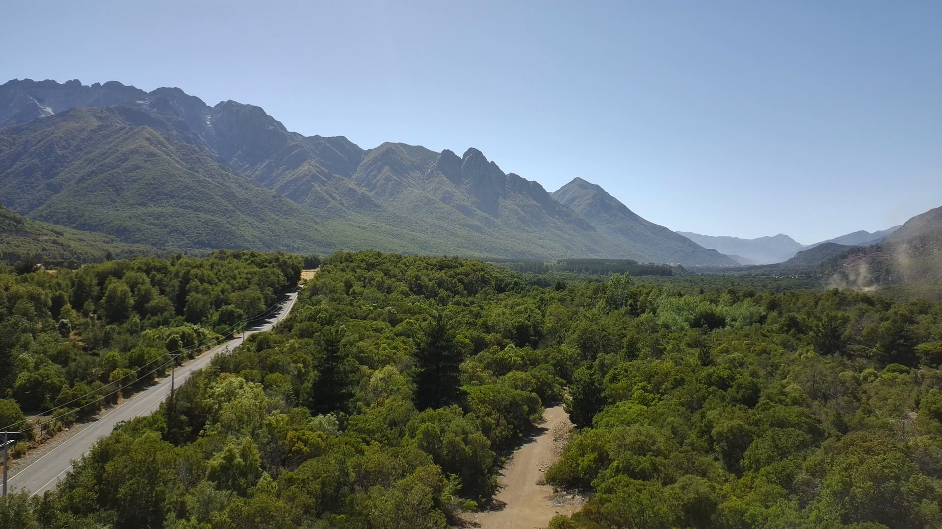 Vista aérea del bosque nativo, el camino y la cordillera en Parcelas Las Pilcas, precordillera de Ñuble, cerca de San Fabián de Alico