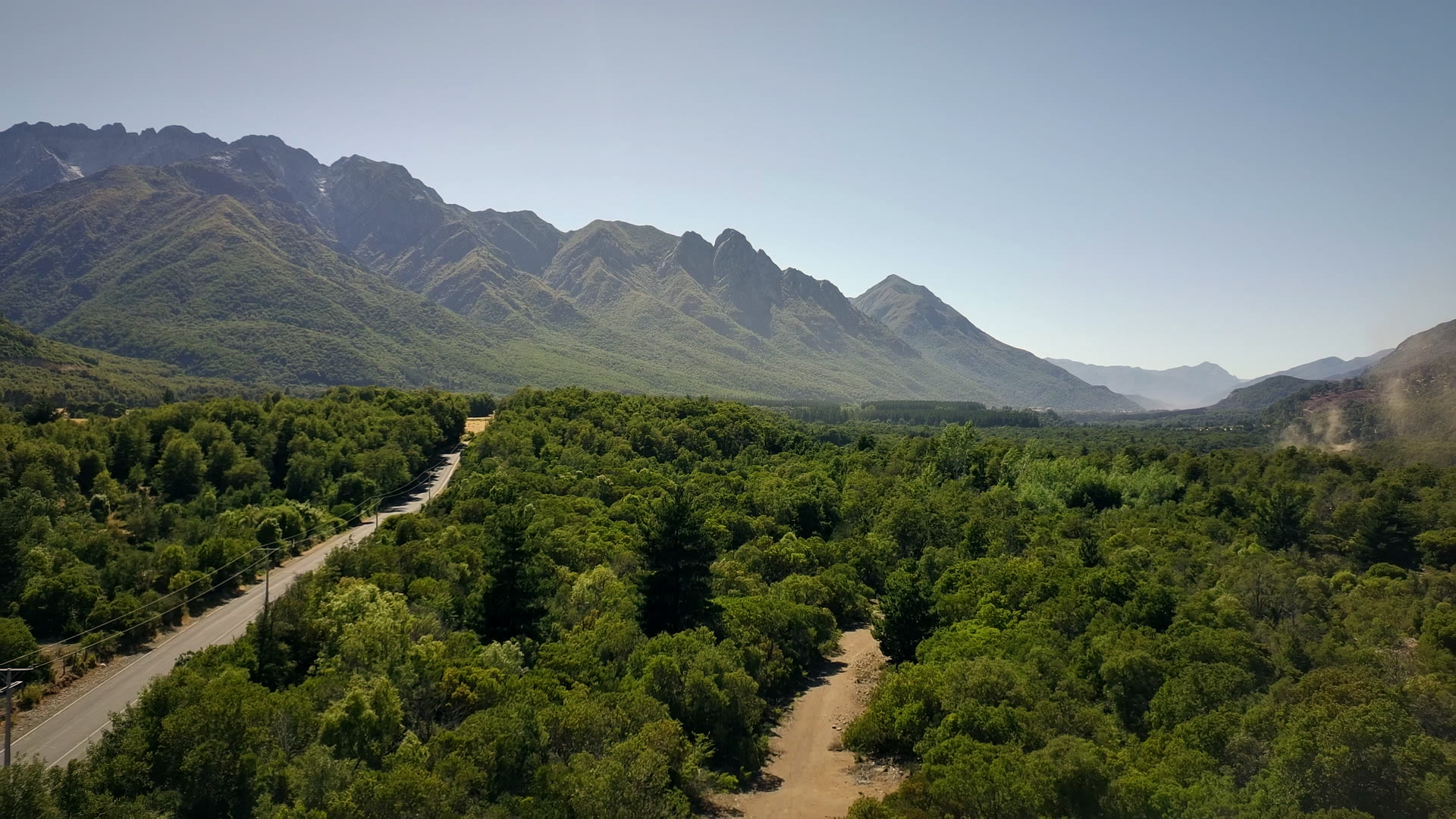 Vista aérea del bosque nativo, el camino y la cordillera en Parcelas Las Pilcas, precordillera de Ñuble, cerca de San Fabián de Alico